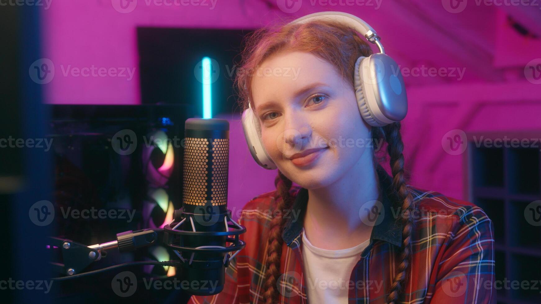 Caucasian woman teenager girl student female streamer blog cyber sport gaming addiction influencer blogger vlogger computer game radio stream mic broadcast looking at camera smiling neon light photo