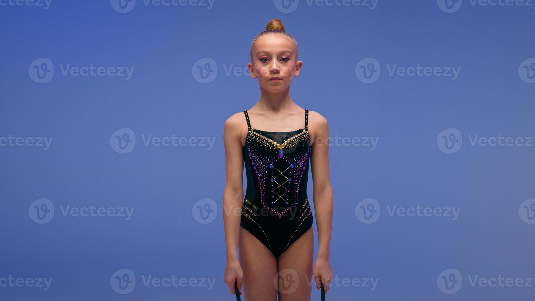 Caucasian little kid sport girl child daughter schoolgirl student dancer gymnast young female athlete juggler on blue background gymnastics element twirling spinning juggling clubs motion in studio photo