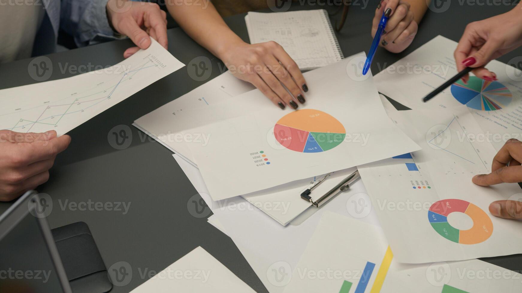 Top view hands and documents on table unknown group business men women team coworkers planning work data graphs charts papers analysis project analyze paperwork corporate teamwork brainstorm at office photo