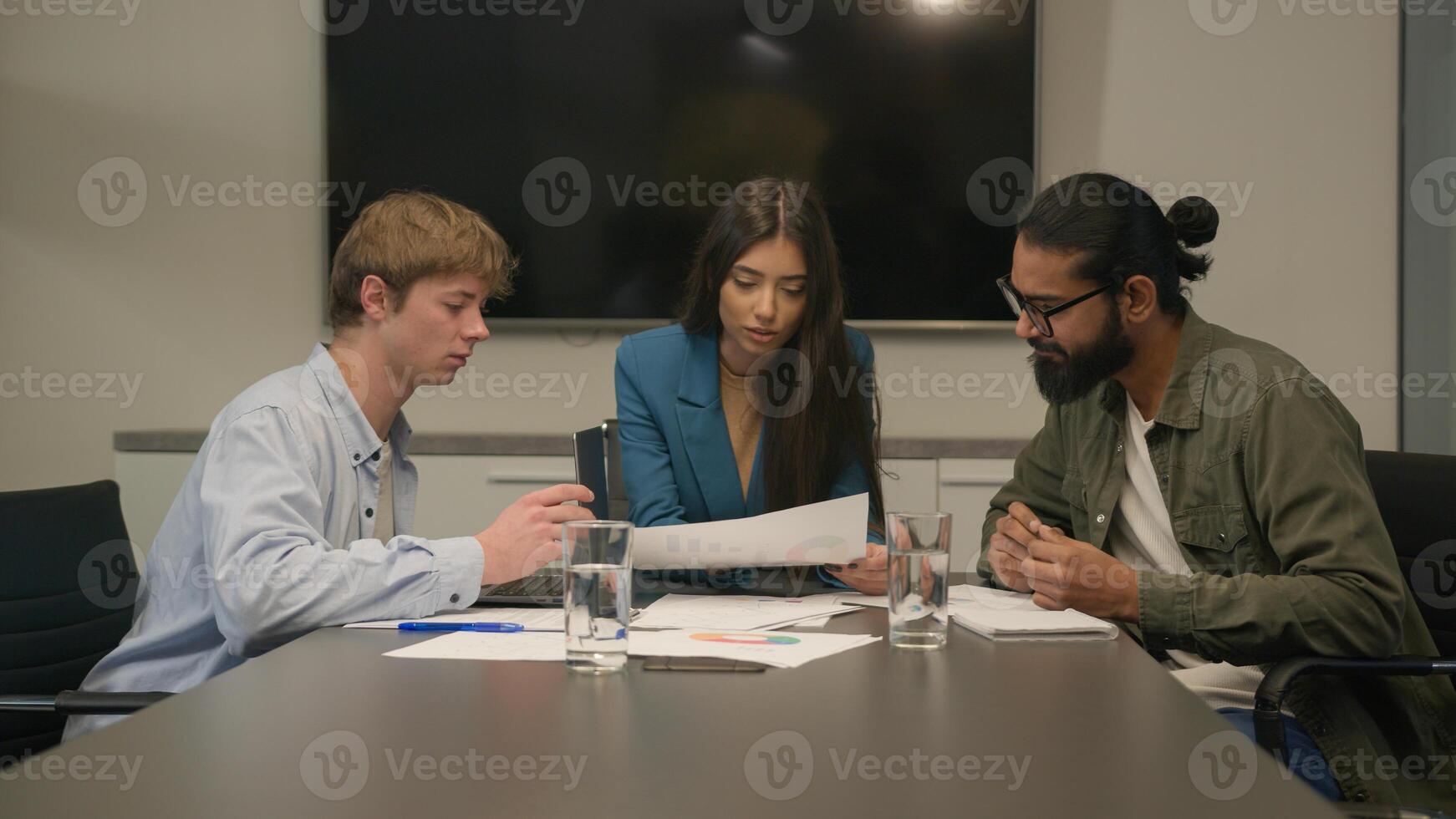 Three multiracial businessmen businesswoman team reviewing sales data documents paperwork teamwork discussion diverse business men woman colleagues coworkers company brainstorm talk at table at office photo