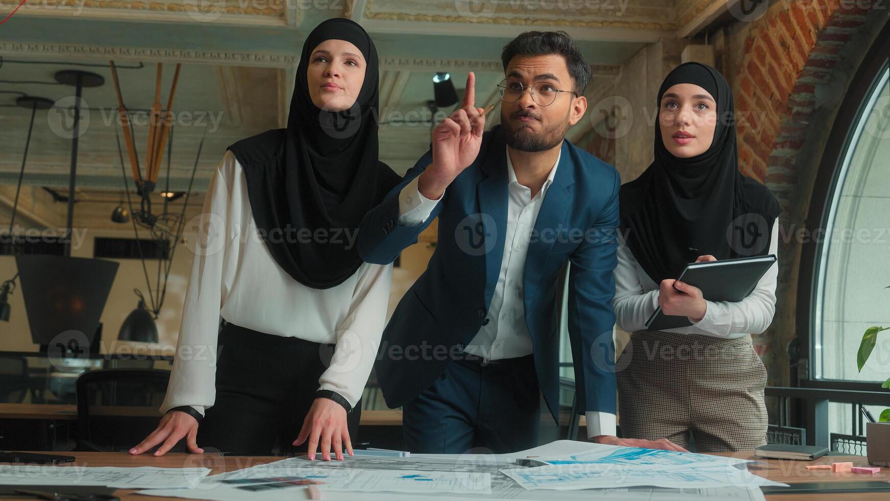 Indian man muslim hijab women business team architects engineers designers builders male female drawing building floor plan construction blueprint sketch on table paperwork planning discuss in office photo