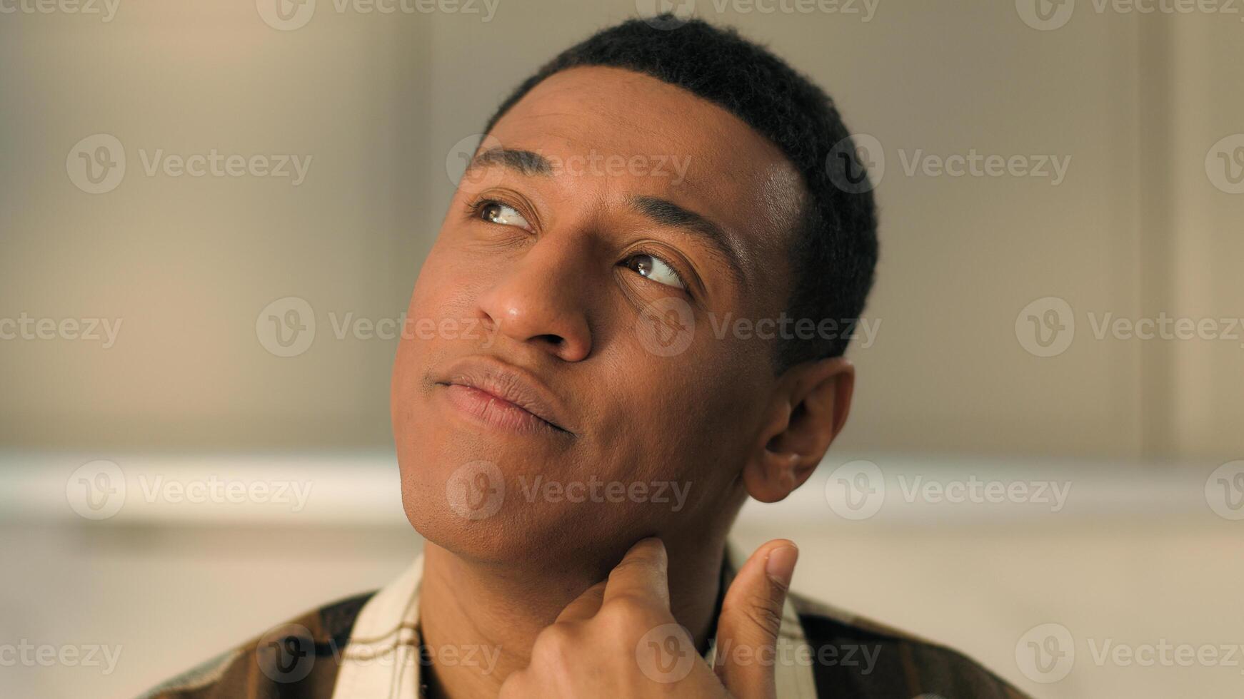 Close up face portrait pensive African American ethnic man healthy guy male homeowner boyfriend dad father puzzled thoughtful looking up think ponder thinking doubt loan mortgage debt bankruptcy home photo