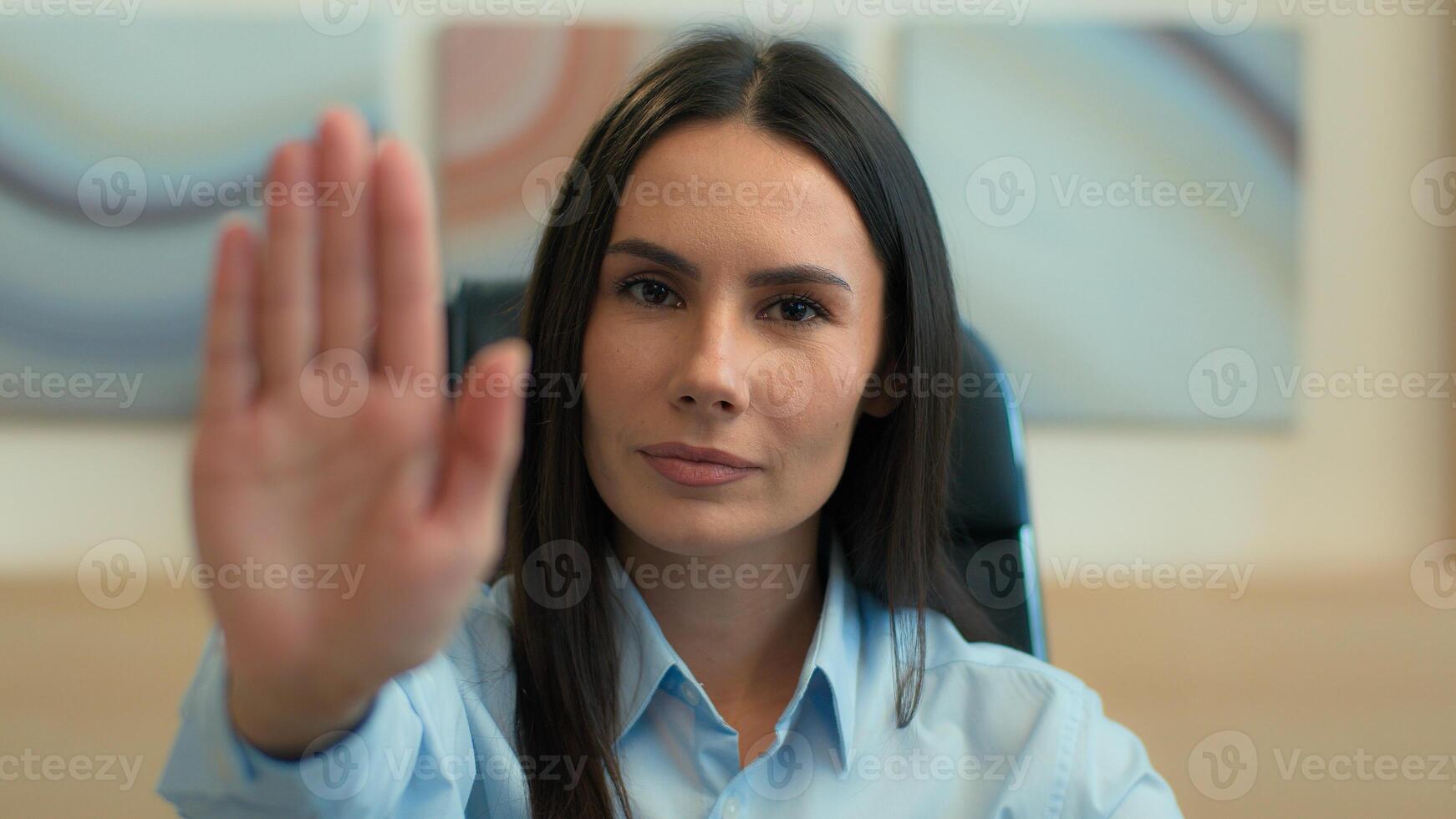Business portrait indoors Caucasian serious strong woman business girl female businesswoman office employer boss leader outstretch palm stop hand gesture no not never symbol forbid reject deny refuse photo