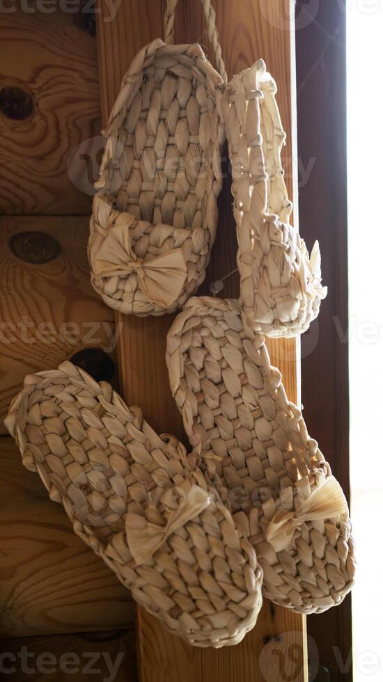 Bast shoes woven from the bark hang. Handmade, old shoes, traditional. Close-up photo