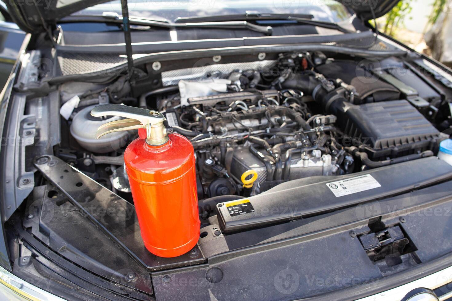 Car fire extinguisher on the background of the car engine. Extinguishing class of fire extinguisher, expiration date. Copy space for text photo