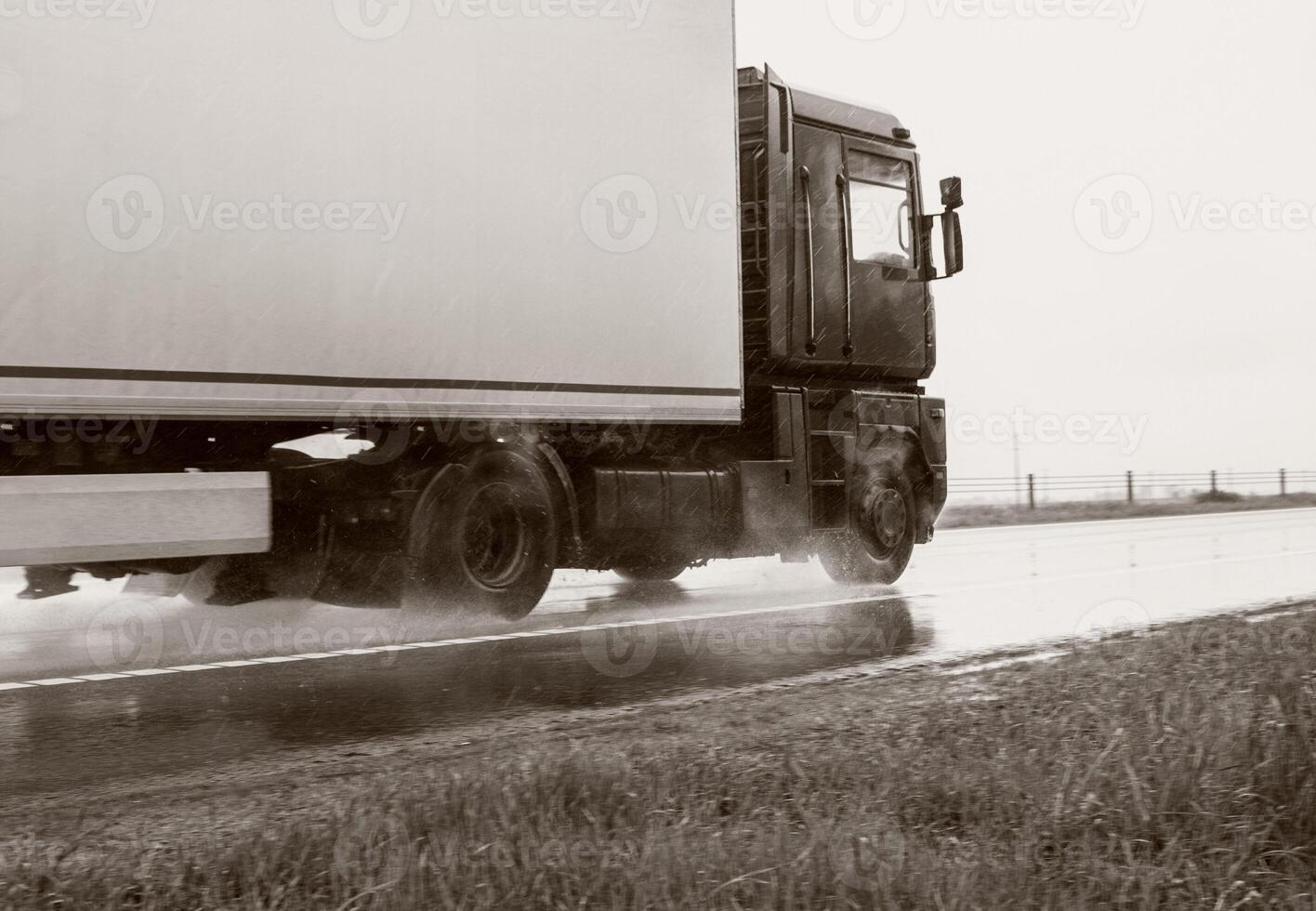 A truck with a semi-trailer transports cargo in bad rainy weather with insufficient visibility. Black and white photography. Road traffic accident. Copy space for text photo
