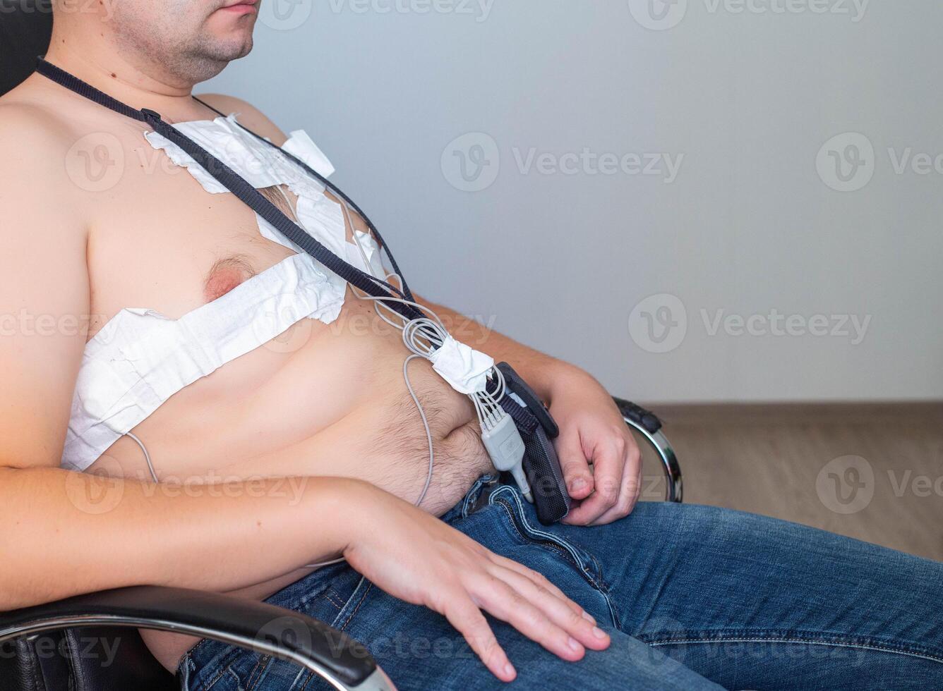 An obese man undergoes a Holter monitoring of the heart. Control of blood supply and disorders of the heart after myocardial infarction, electrocardiogram photo