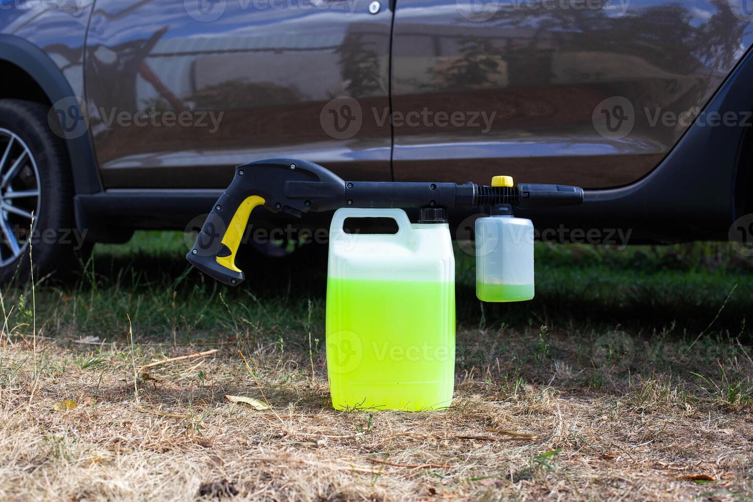 a canister with shampoo and a nozzle for a high-pressure washer a foam generator against the background of a car. Car wash and care. Copy space for text photo