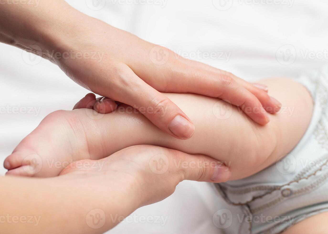Mother massages baby on legs. Newborn skin care, close-up photo