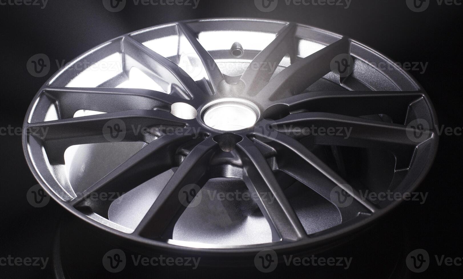 Modern beautiful car alloy wheel in the form of rays that is highlighted by rays of light and sparkle, black background photo