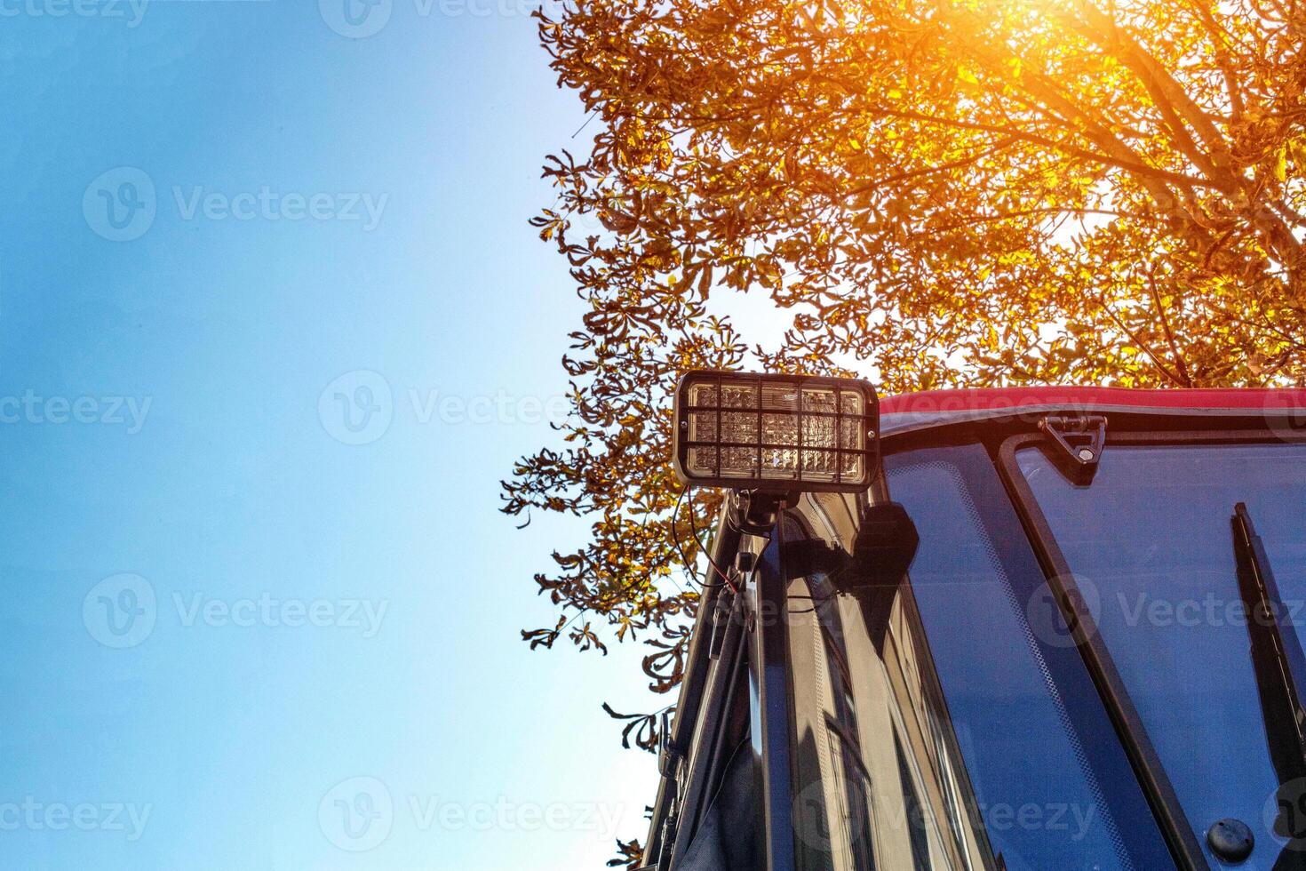 Rear lights in the tractor for traffic safety and illumination against the background of an autumn tree and a blue sky. Copy space for text photo