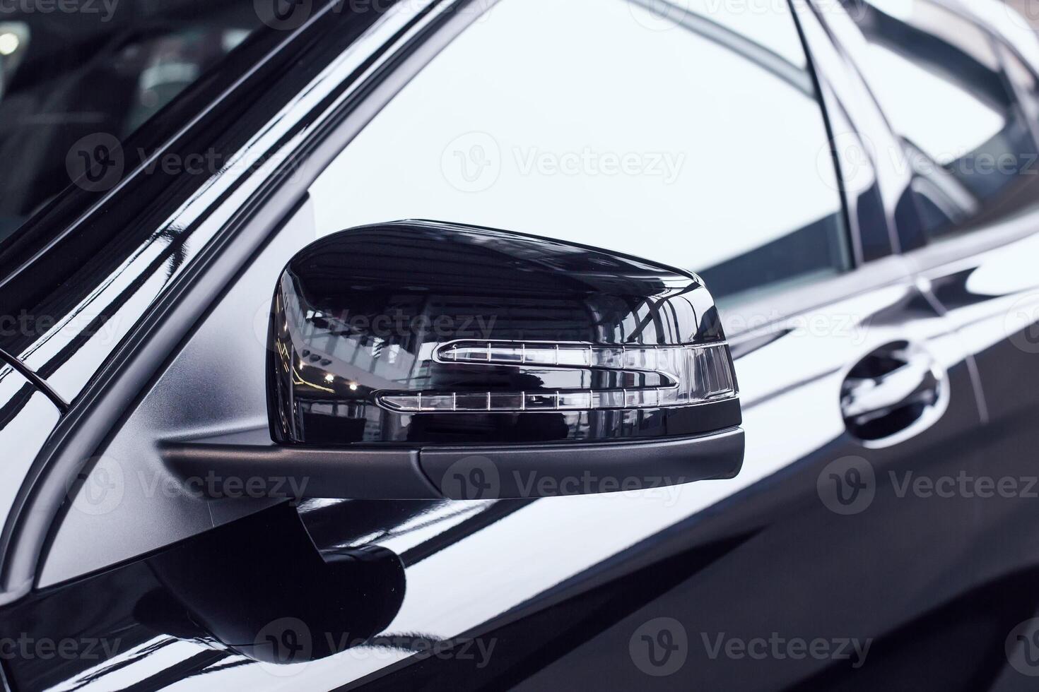 Modern beautiful side rear-view mirror in a new car with a built-in direction indicator. Black car at a car dealership, aerodynamic photo