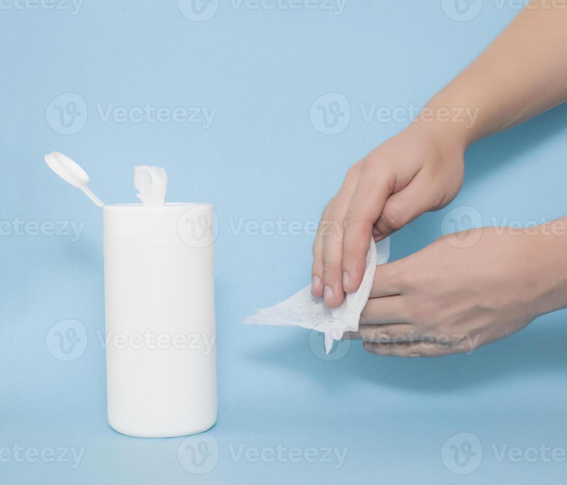 A man rubs his hands with a wet disinfectant wipe on a blue background. The concept of antiseptic wipes against coronovirus and bacteria, hand hygiene photo