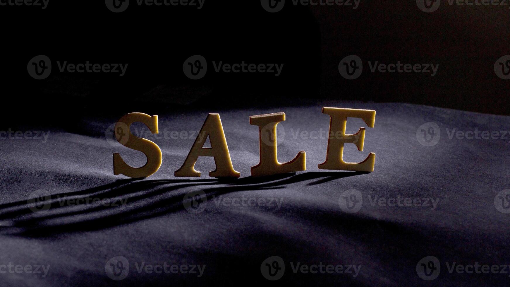 Wooden letters on a dark background with beautiful lighting. Discounts and sales concept photo