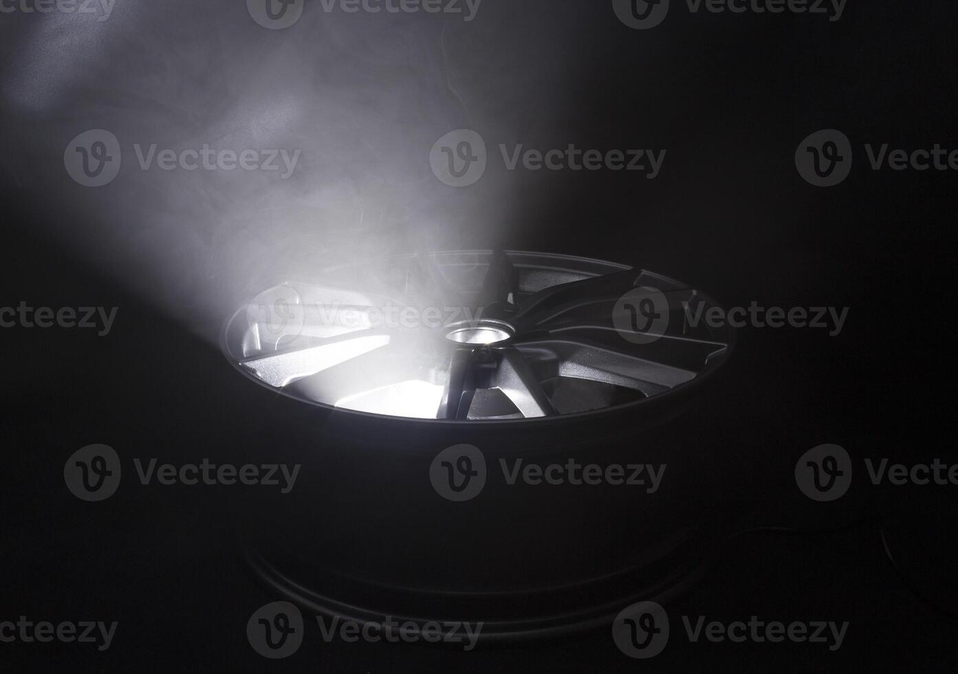 Modern beautiful car alloy wheel in the form of rays that is highlighted by rays of light and sparkle, black background photo