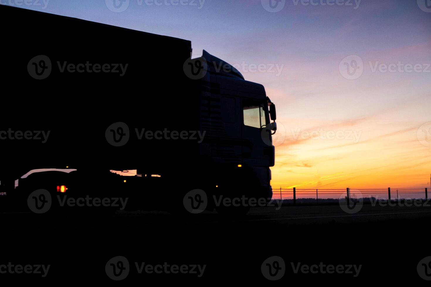 A truck with a trailer rides on the motorway at night against the backdrop of an orange sunny sunset. The concept of the regime of work and rest of truckers, copy space, tachograph photo