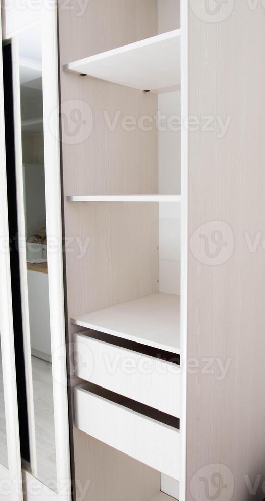 White closet with shelves for clothes in the hallway, close-up. Dressing room, photo
