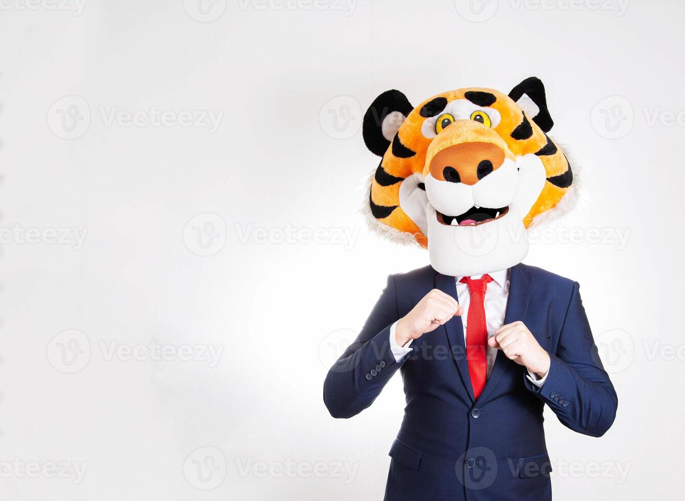 Dancing man in a business suit and a tiger mask on his head on a white background, humor. Copy space for text photo