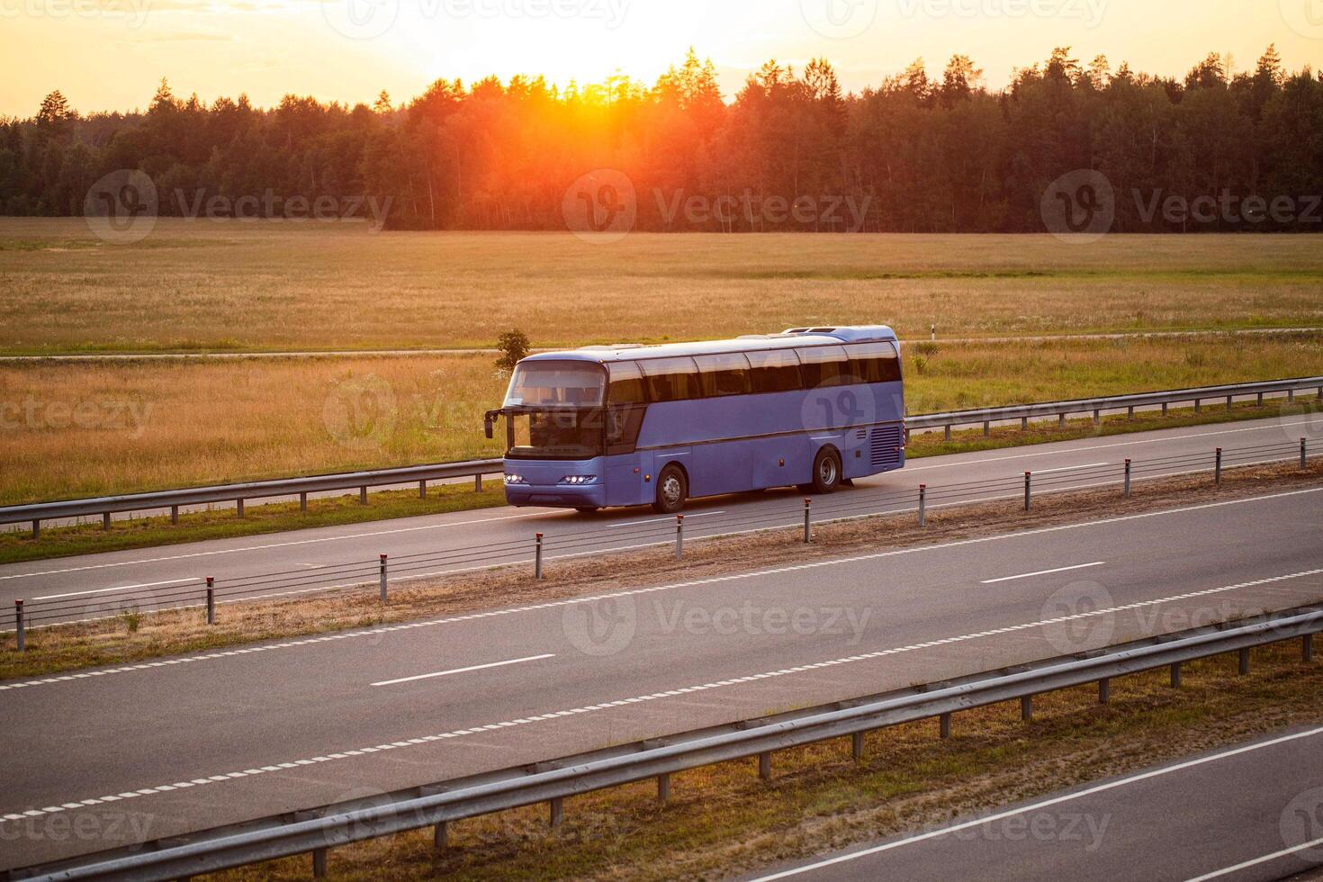 A blue comfortable bus transports passengers along the highway in the evening against the backdrop of sunset. Concept of traveling to another country by bus from a travel agency, convenience photo