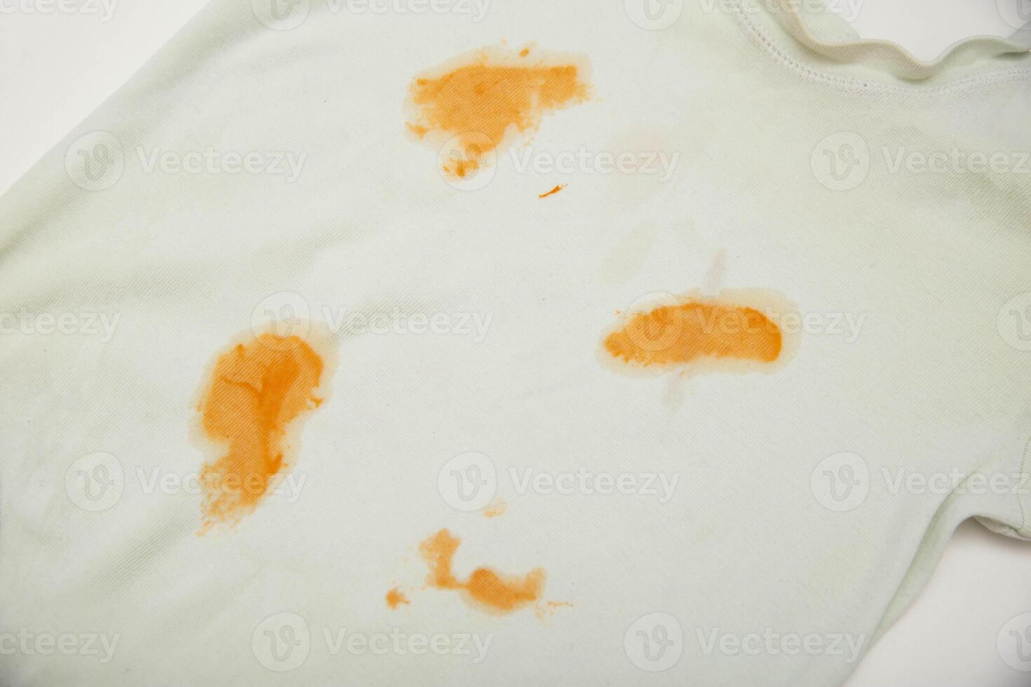 Orange stains on children's clothes from fruit puree. The concept of cleaning stains on clothes with an oxygen stain remover, close-up photo