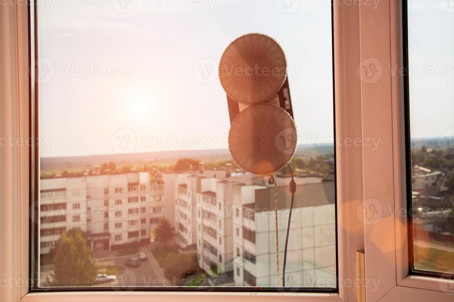 A modern vacuum robot window cleaner washes glass from dirt and stains on a pvc balcony frame. Fall safety. Copy space for text photo
