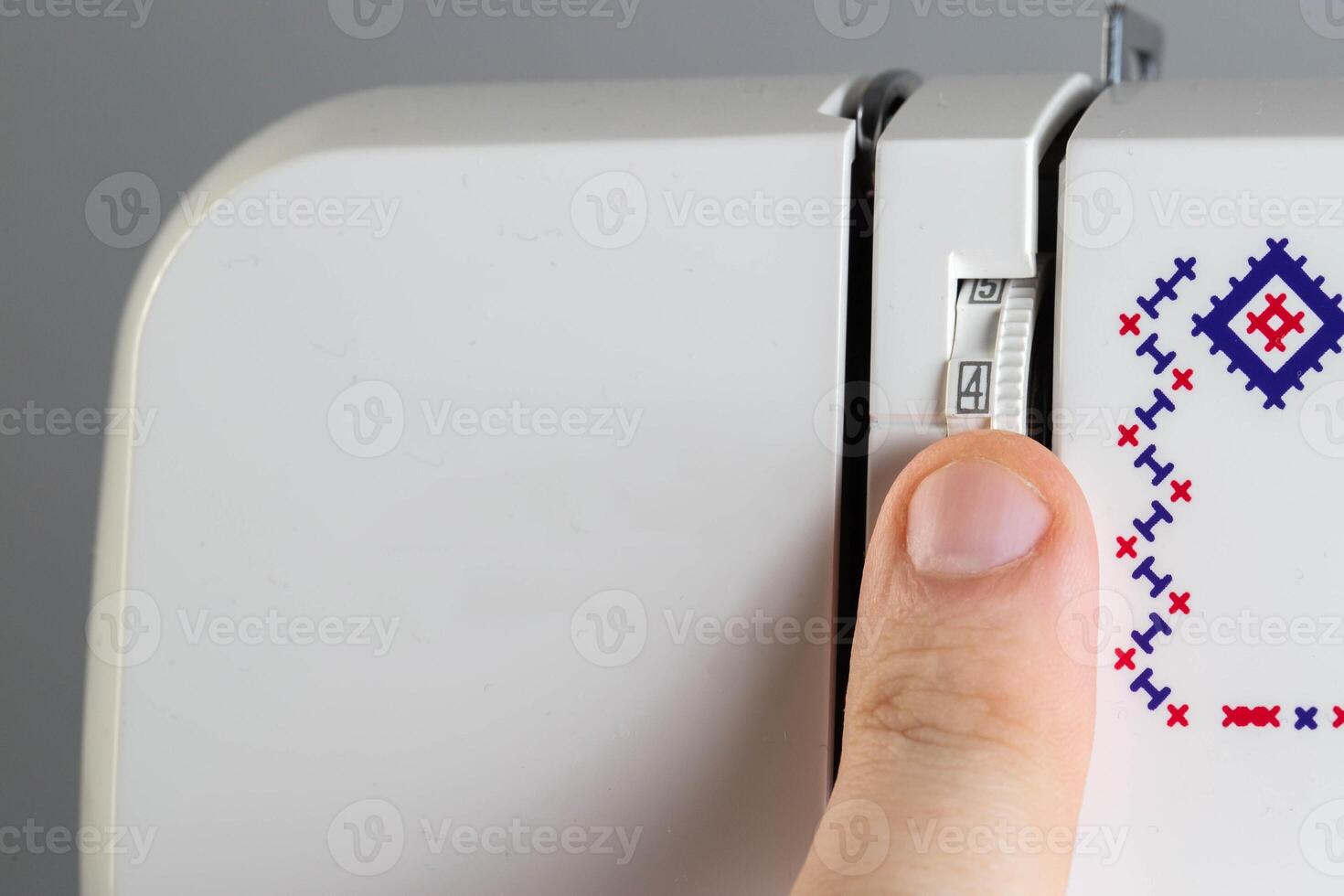 A seamstress's finger adjusts the stitch length dial of a sewing machine, macro. Stitch regulator photo