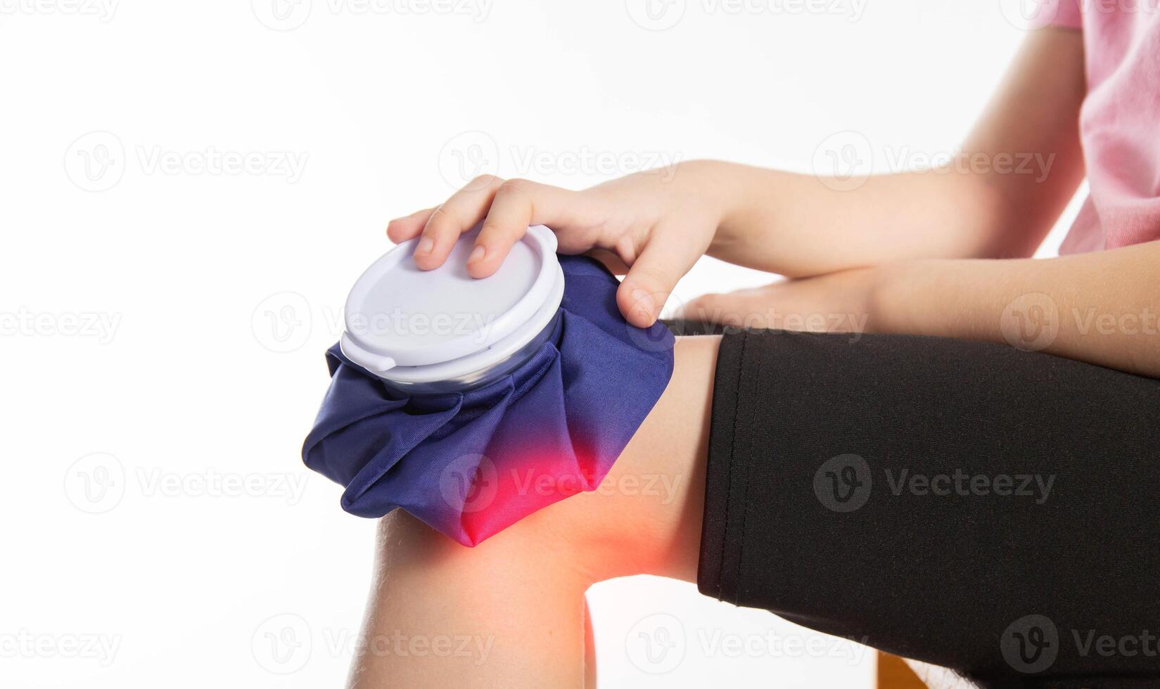 A girl applies a blue medical bag with ice to her knee joint for a knee injury. Local cryotherapy. Pain relief with cold, close-up photo