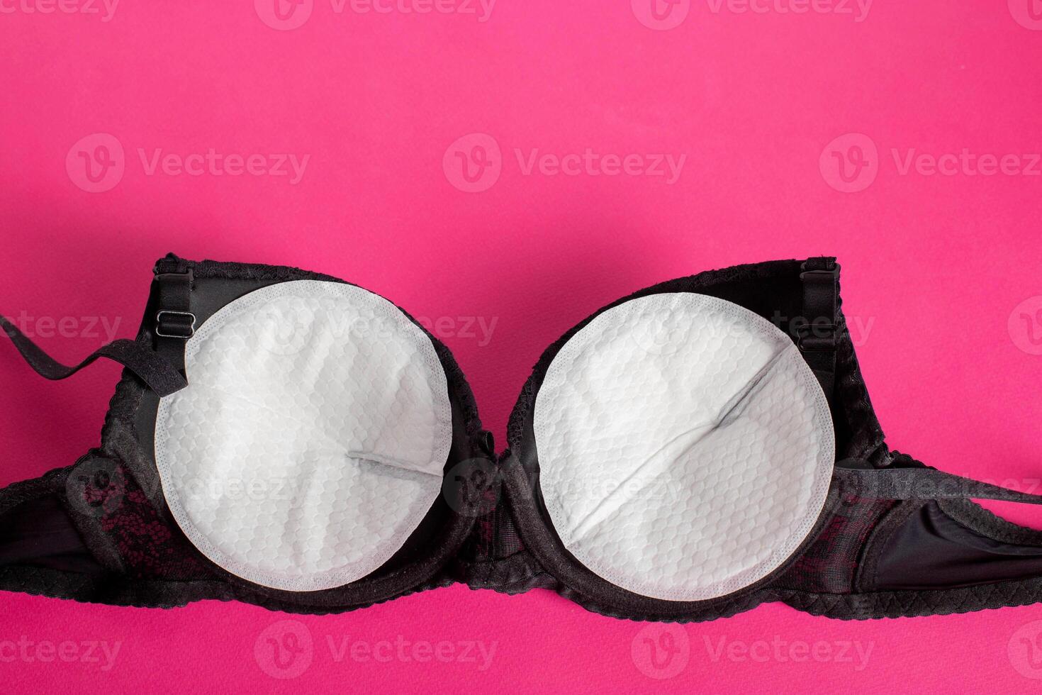 Black bra with liners for the female breast against the flow of milk on a pink background. Womens breast pads, lactation photo