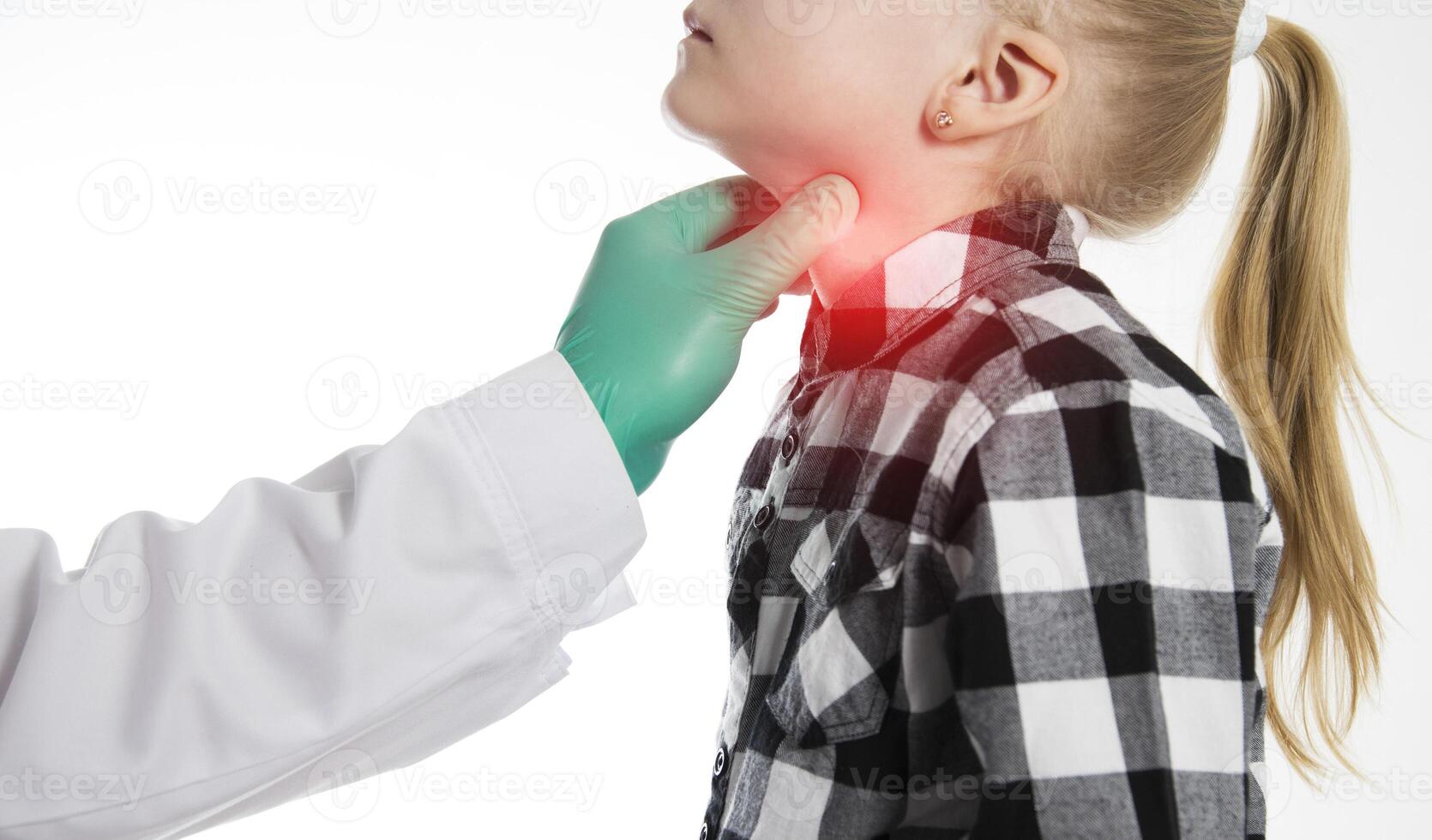 The hand of an endocrinologist palpates the thyroid gland of a seven-year-old girl. Concept of dysfunction of thyroid hormones. Lack of iodine, hypothyroidism. Copy space for text photo