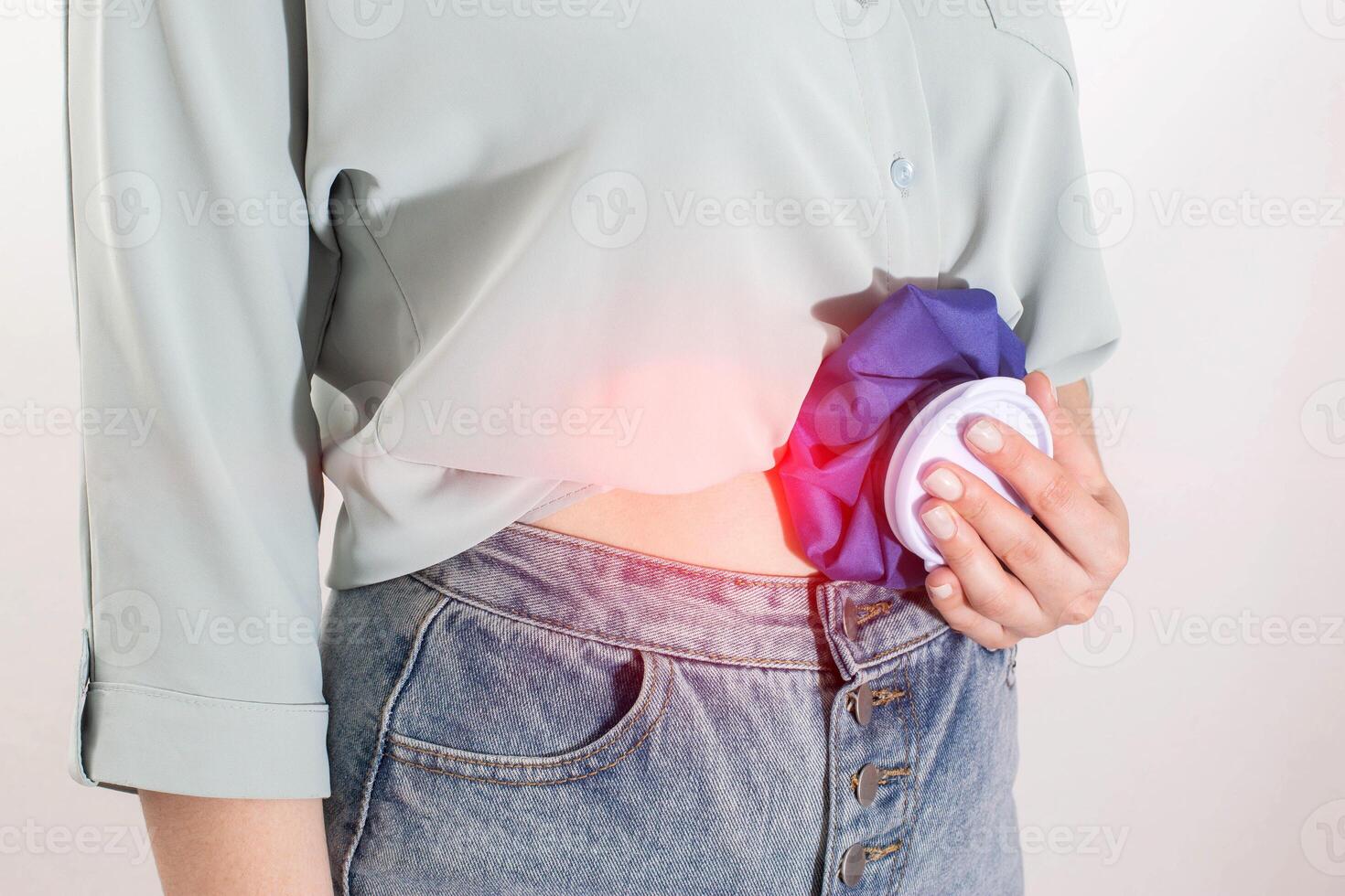 The girl applies cold in a medical bag to relieve abdominal pain and pain relief. The concept of cold compresses for lubricants and abdominal pain, close-up photo