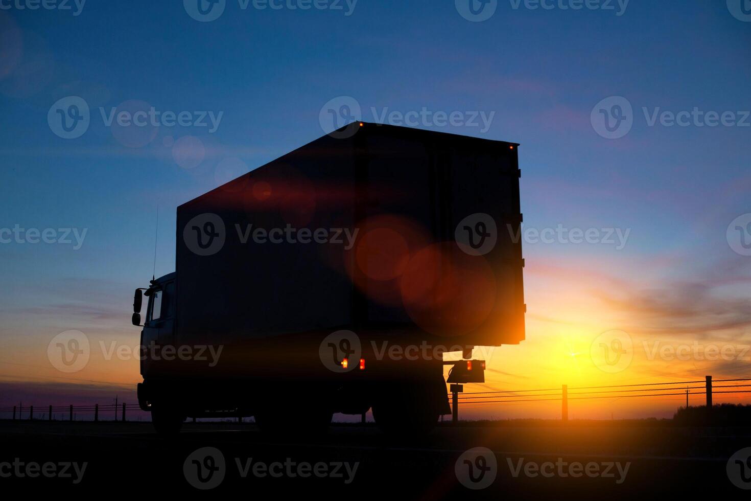 Truck driver transports cargo on a truck against the backdrop of sunset at night. The concept of compliance with the work and rest regime of drivers photo