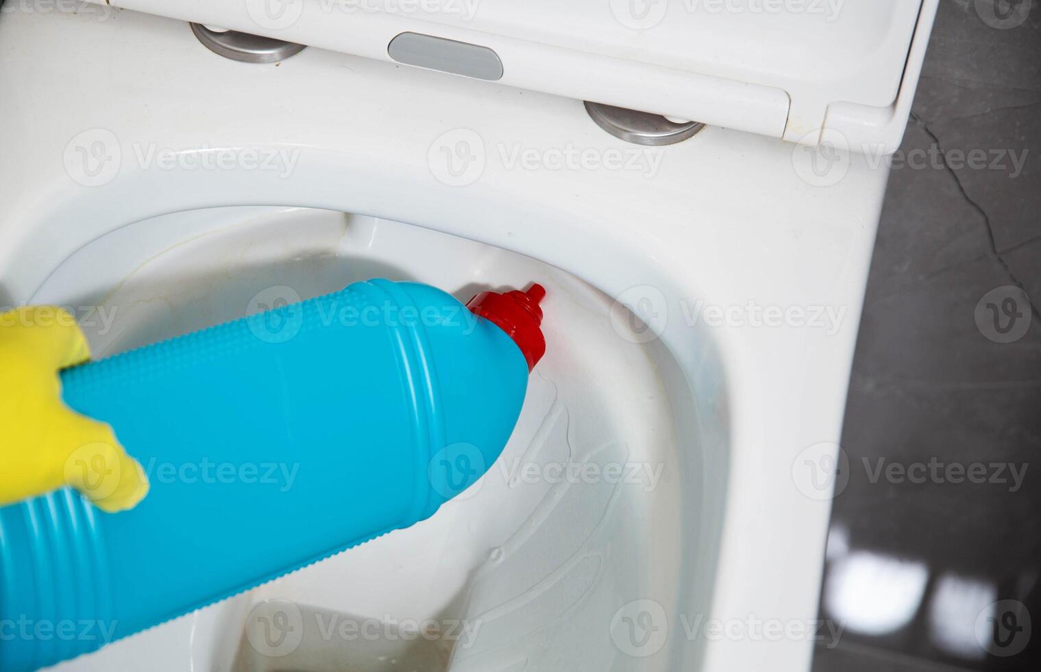 The hands of a girl in yellow rubber gloves wash the toilet with a modern cleaning agent from viruses and bacteria, hygiene. Cleaning company services photo