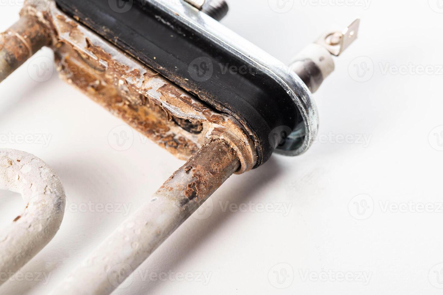 Old electric heating element from a washing machine on a white background. Scale and rust due to hard water, close-up photo