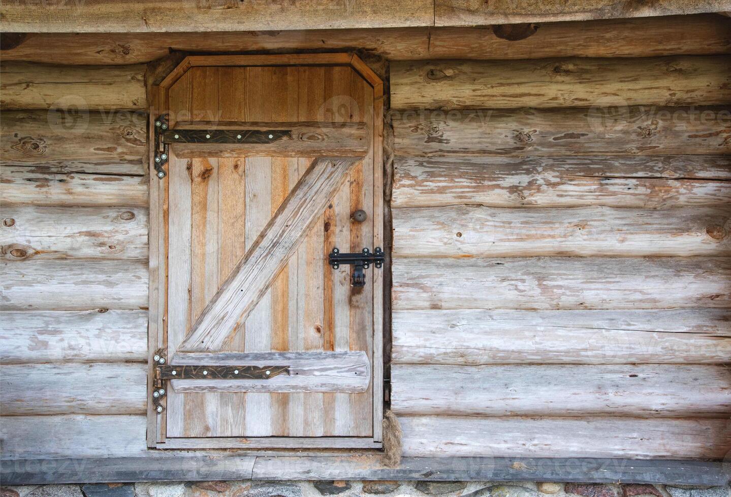 Old wooden door with a metal lock in a rustic log house, antique. Copy space for text photo