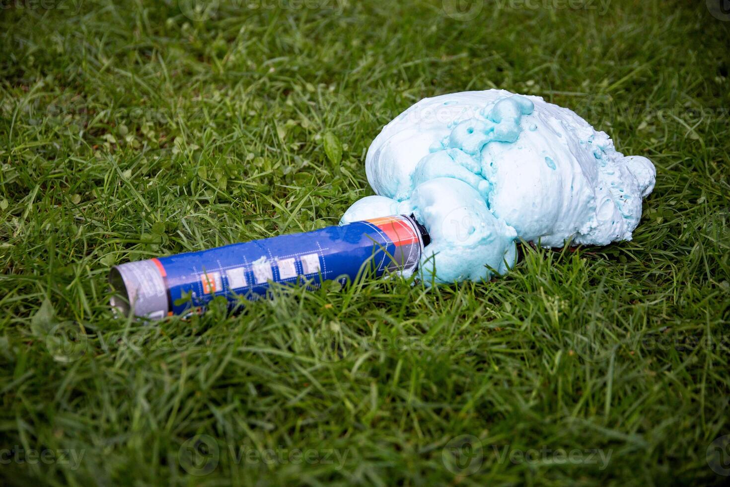 An exploded cylinder with construction foam on the grass. Balloon defect, close-up photo