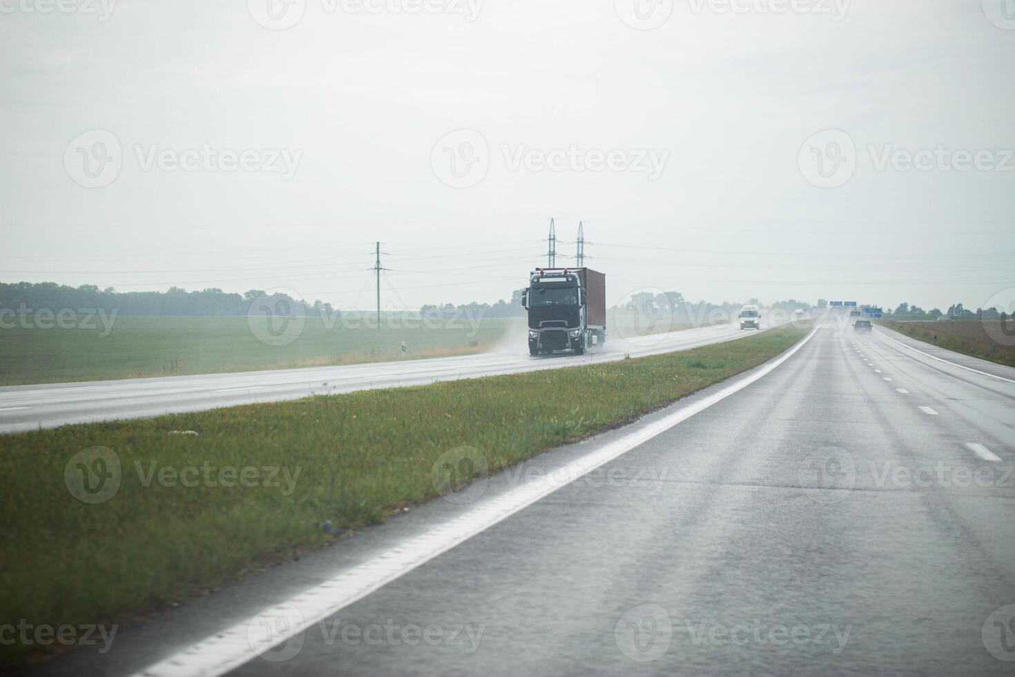 Traffic from cars drives on a highway slippery from rain in cloudy rainy weather. Copy space for text photo