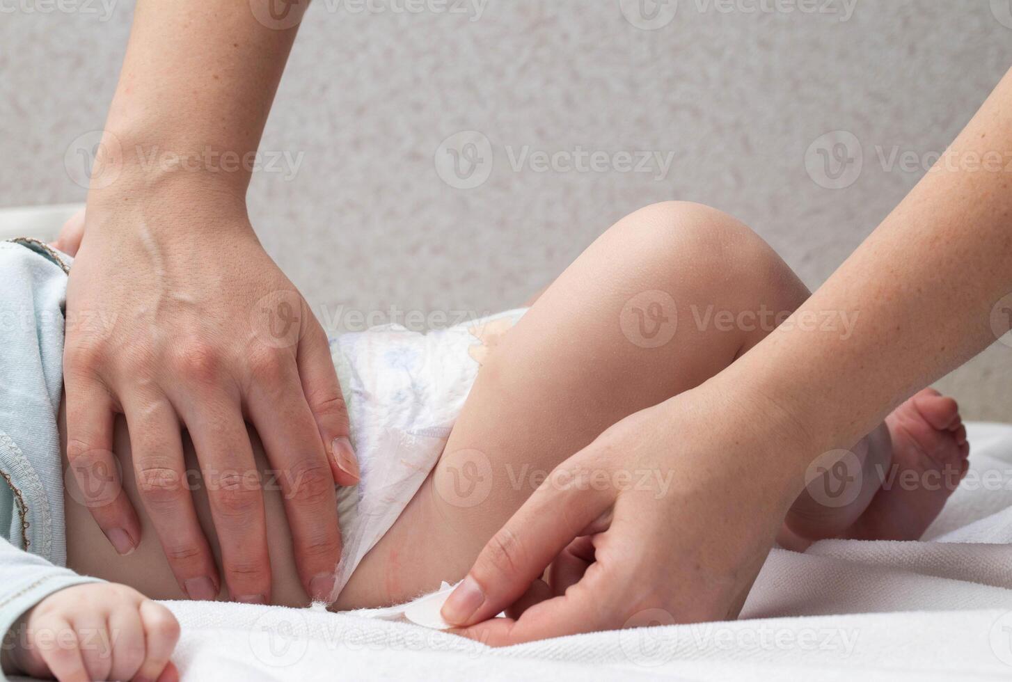 The mother fastens the fasteners and changes the baby's diaper, close-up. Copy space for text photo