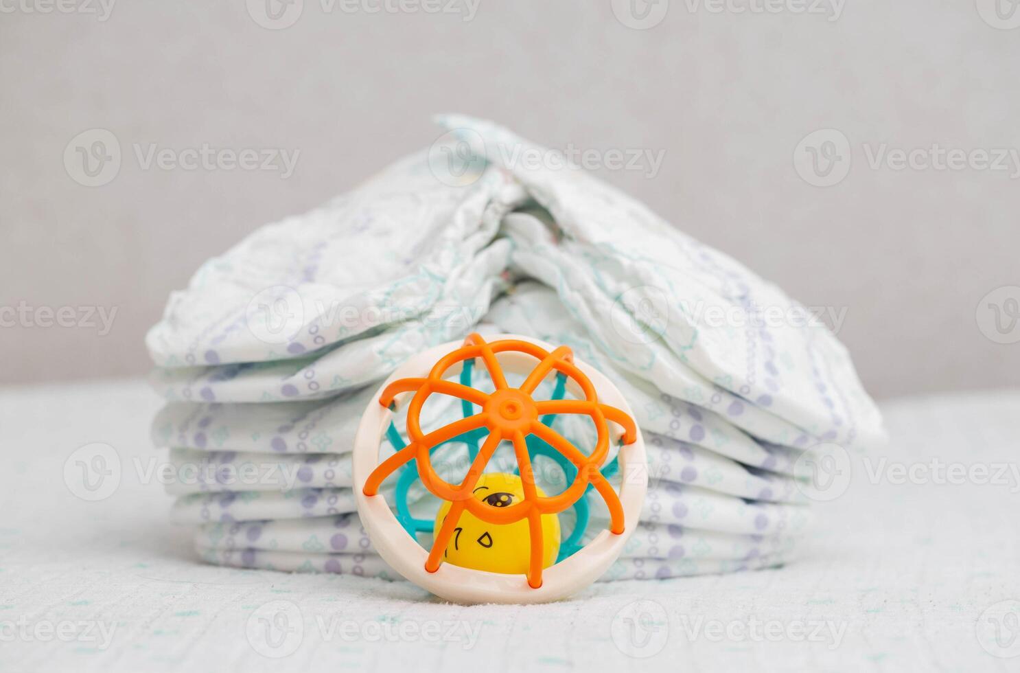 Baby toy on the background of a stack of baby diapers, close-up. Copy space for text photo