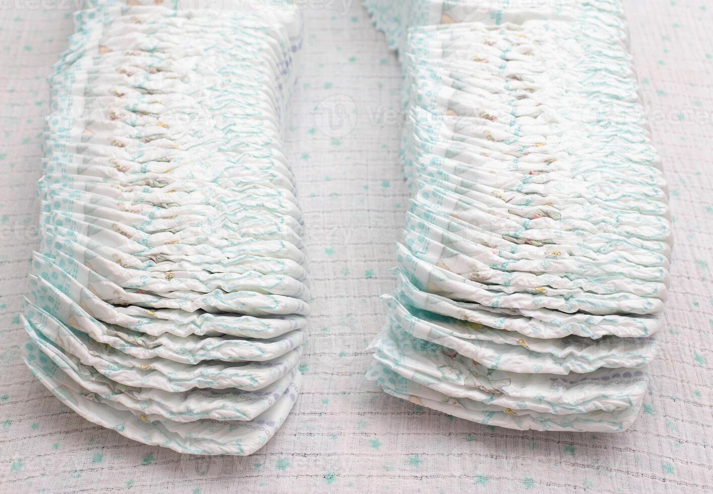 Many stacks of baby soft and comfortable diapers on a white background, close-up photo