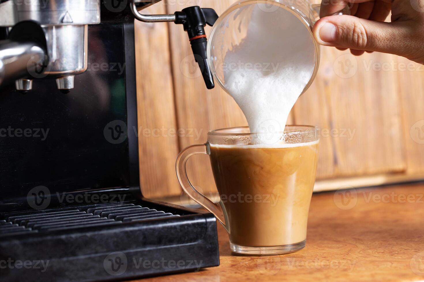 Making coffee with cappuccino milk in a cappuccino machine with a manual cappuccino maker on the background of a wooden table top. Close-up photo
