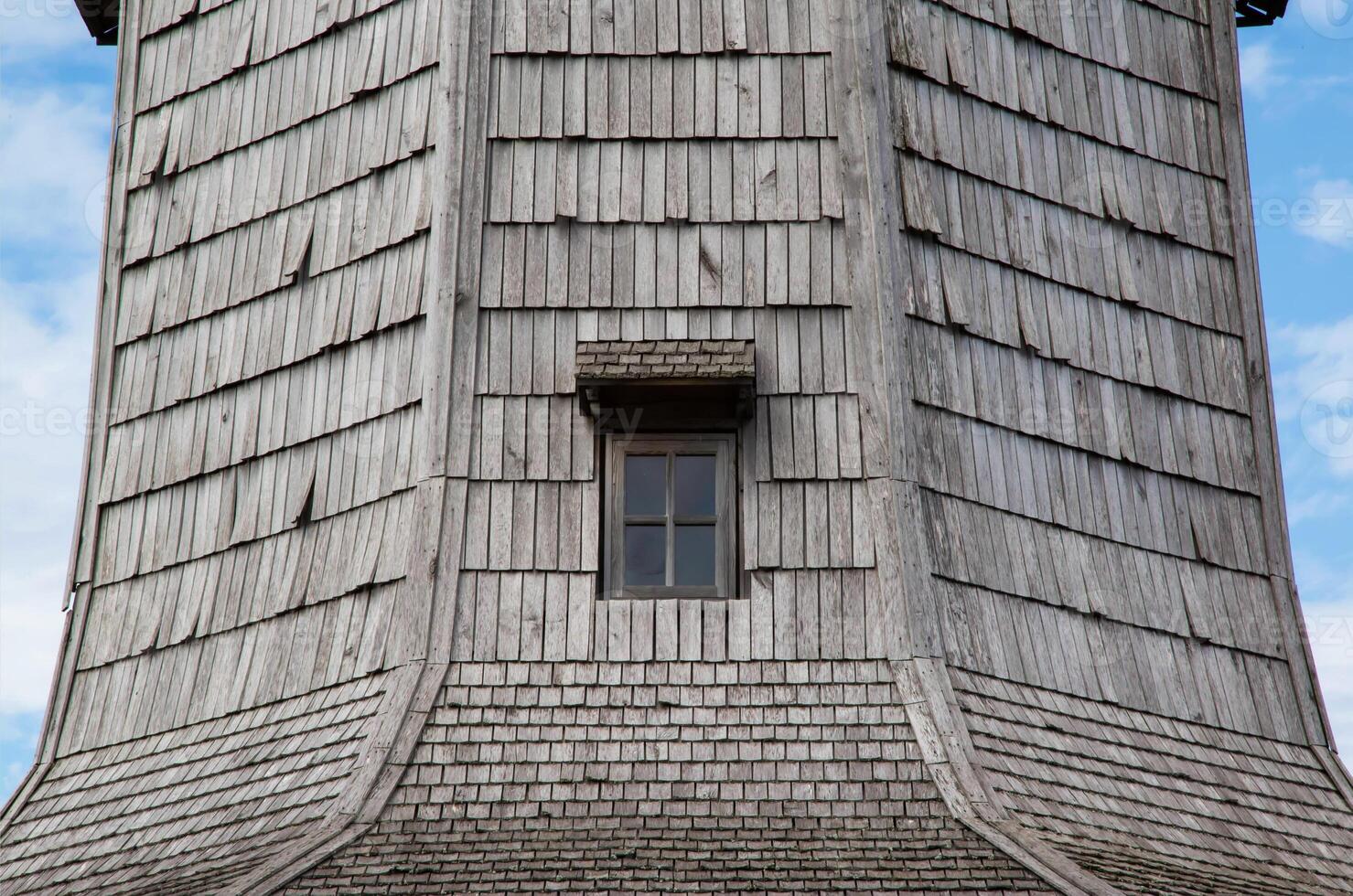 Antique window in a wooden planked wall, close-up. Exterior photo