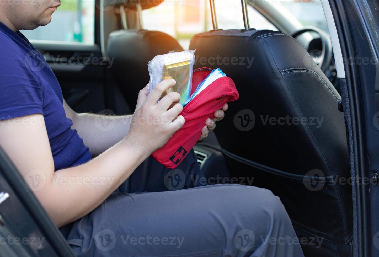 a man opens a car first aid kit in the car. The concept of first aid to the injured person in a road traffic accident. Availability of a first-aid kit when going through a technical inspection photo