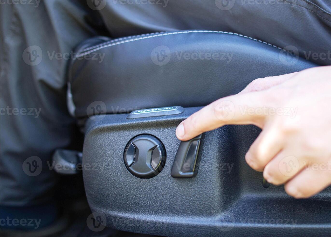 The man presses his finger on the adjustment button for the electric seat in the car. Modern comfortable seat, close-up photo