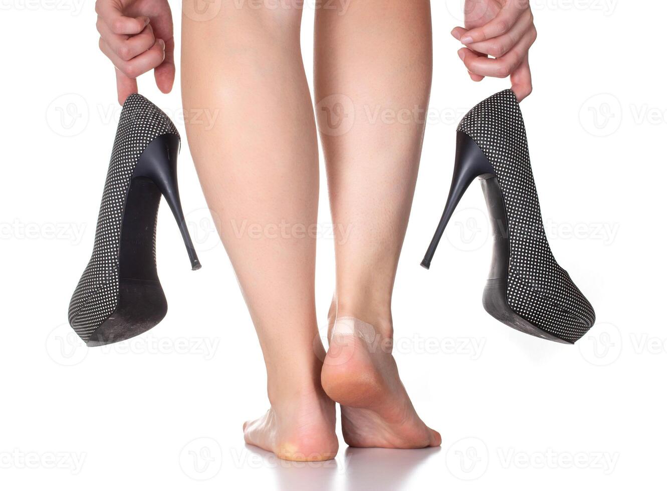 Girl holding high heel shoes on a white background. The concept of uncomfortable shoes and rubbing calluses, isolate photo
