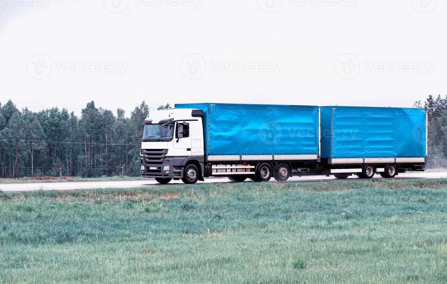 Truck tractor hitch with semi-trailer transports cargo on a country highway with a large tonnage and volume of cargo. Copy space for text. Industry photo