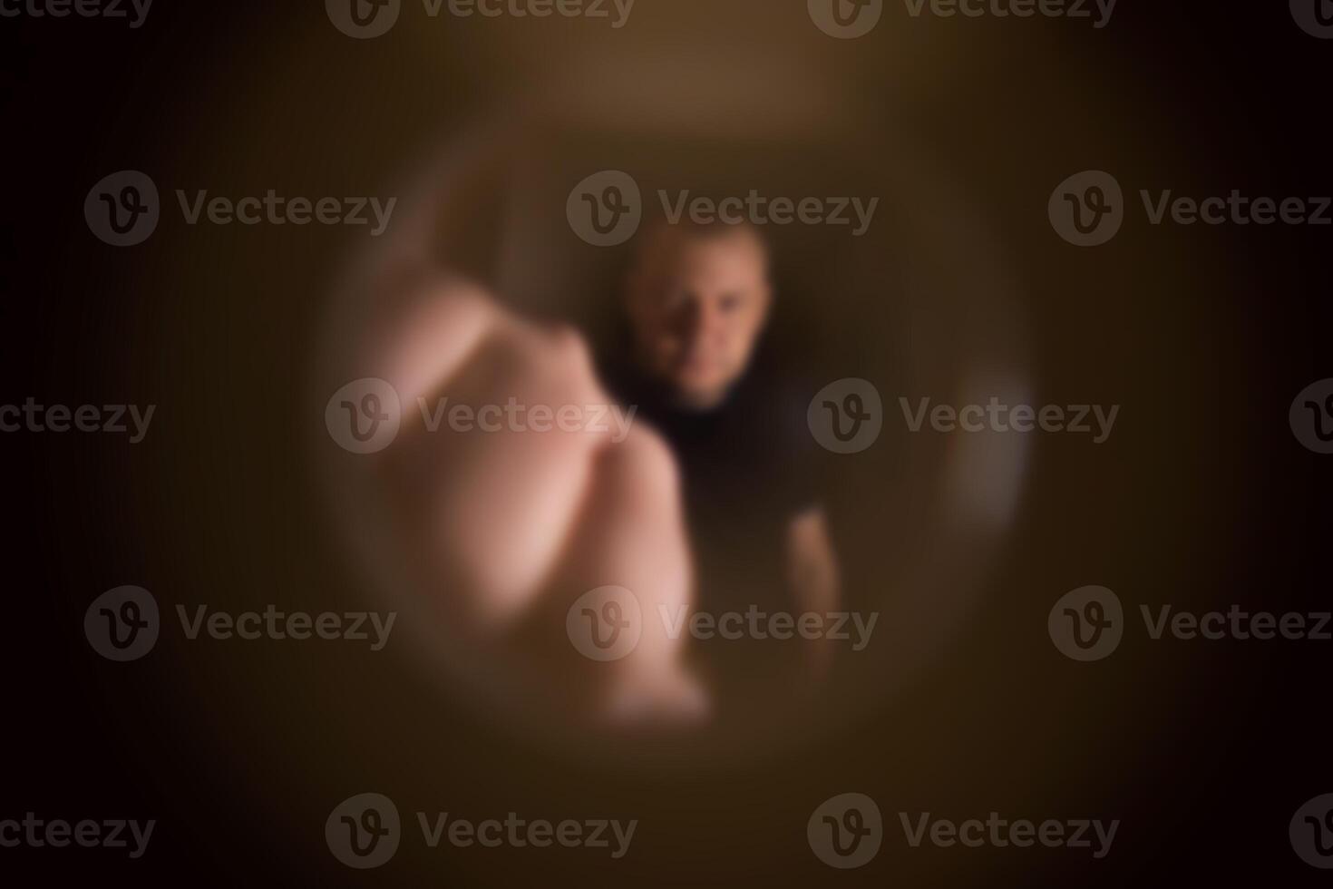 View from the peephole. Angry male neighbor knocking on the front door with his fist, close-up. Blurred photo