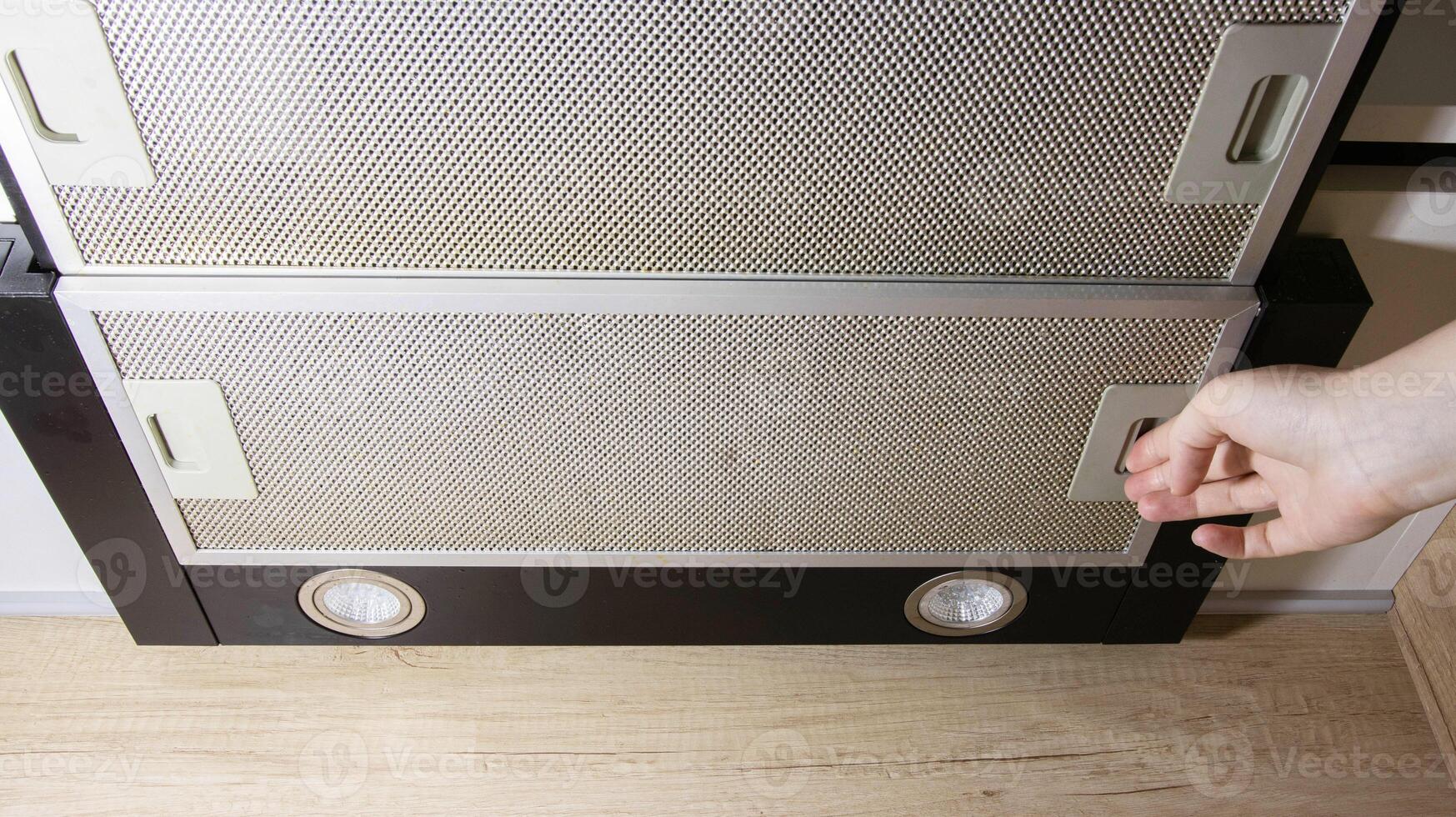 Modern kitchen hood with grease filter for air purification. Replacing the grease filter and maintaining the kitchen hood. photo