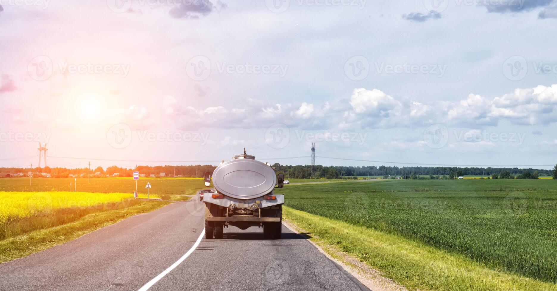The tanker truck transports milk on the background of the fields. Logistics and business in agriculture. Copy space for text, industry, countryside photo