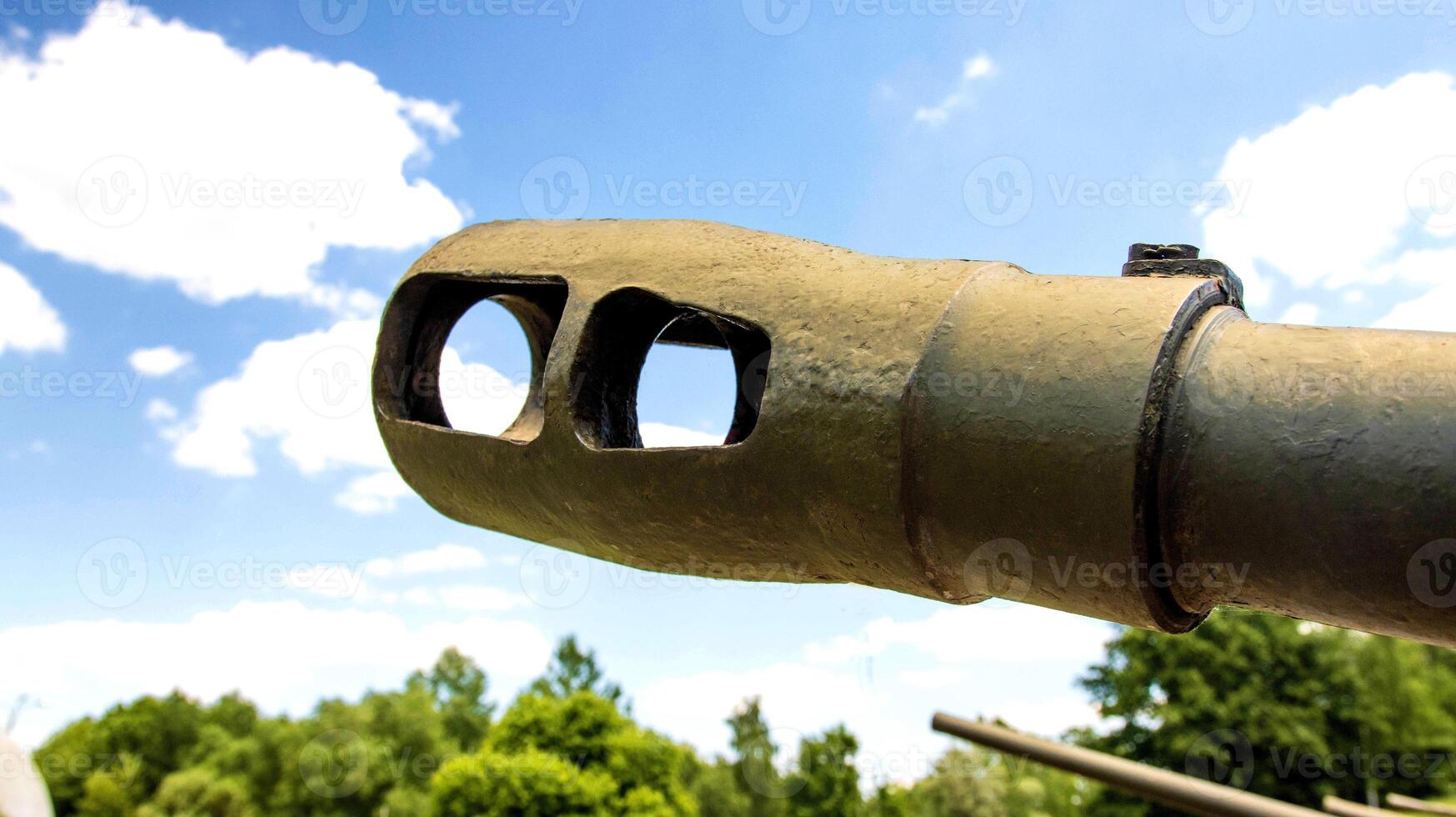 The muzzle of a cannon of a military tank against the blue sky, close-up. The concept of military conflict, aggression. photo