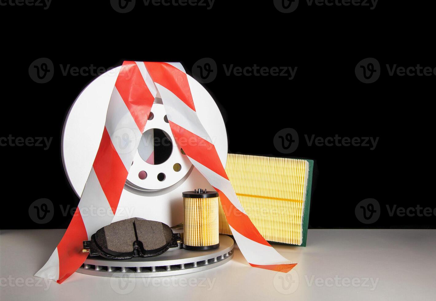 Car parts on a black background with a red white ribbon. The concept of restrictions on the import of auto parts from Europe. Sanctions in the automotive business, copy space for text photo